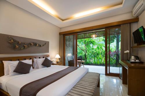 a bedroom with a large bed and a large window at Desak Putu Putera Cottages in Ubud