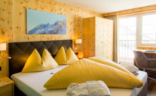a bedroom with a large bed with yellow pillows at Wohlfühlhotel Hubertushof in Stuben am Arlberg