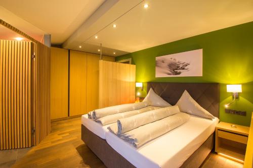 a bedroom with a large bed with a green wall at Wohlfühlhotel Hubertushof in Stuben am Arlberg