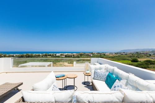 a living room with white furniture and a view of the ocean at Triton Sea View Villa in Georgioupolis