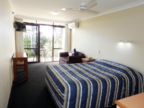 a person laying on a bed in a bedroom at Mt Tamborine Motel in Mount Tamborine