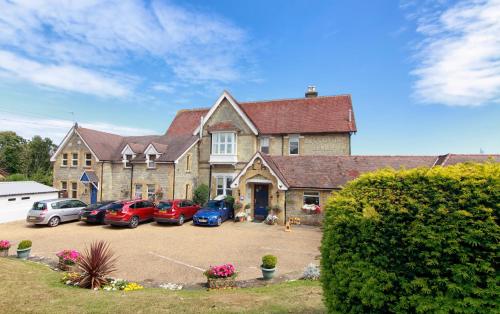 a large house with cars parked in a parking lot at Luccombe Hall Hotel in Shanklin