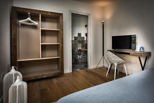 Schlafzimmer mit einem Bett, einem Schreibtisch und einem TV in der Unterkunft Teku Sardinia Boutique Hotel in Bari Sardo
