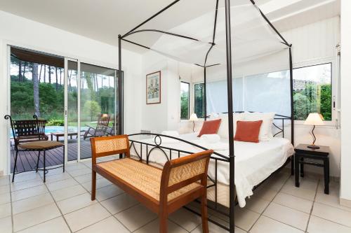 a bedroom with a four poster bed and a patio at Madame Vacances Les Dunes de la Prade in Moliets-et-Maa