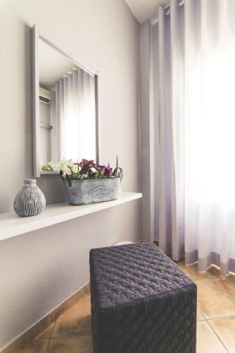 a room with a mirror and a stool in front of a window at Teatro Deluxe Rooms in Kato Rodini