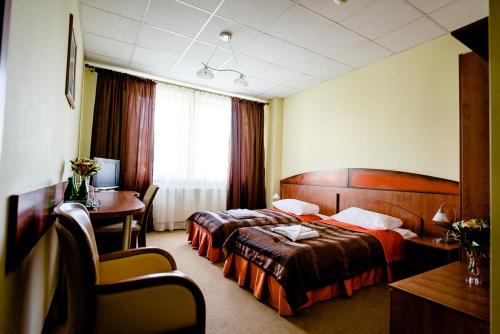 a hotel room with two beds and a desk at Hotel Stal in Stalowa Wola