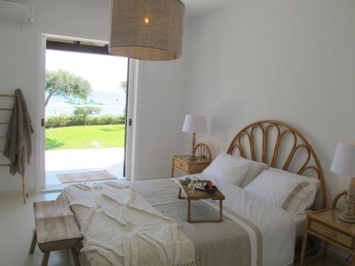 a bedroom with a bed with a table and a window at Seafront Calista Beach House With Garden in Glyfada