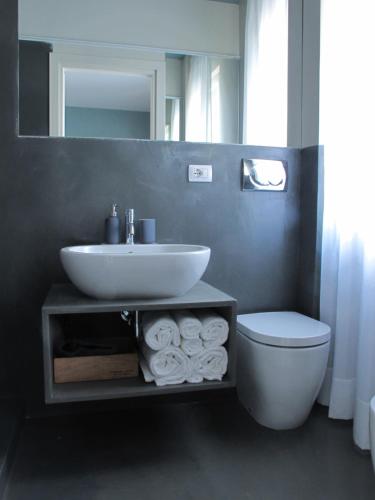 une salle de bain avec un lavabo, des toilettes et un miroir dans l'établissement Avolio Tailored Rooms, à Syracuse