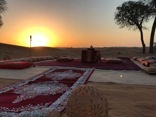 a table in the desert with the sunset in the background at Bedouin Oasis Desert Camp- Ras Al Khaimah in Ras al Khaimah