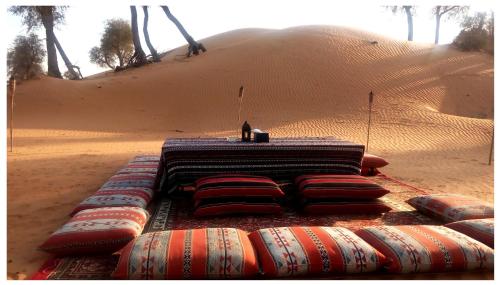 a table in the middle of a desert with pillows at Bedouin Oasis Desert Camp- Ras Al Khaimah in Ras al Khaimah