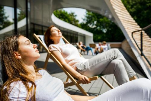 two women sitting in rocking chairs outside a building at Jugendherberge Bayreuth in Bayreuth