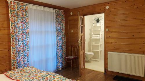 a bedroom with a bed and a bathroom with a toilet at Leonówka Bieszczady in Cisna