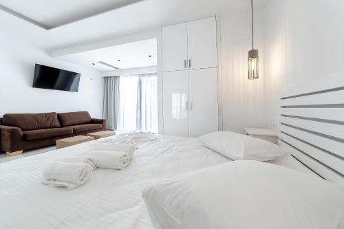 a white bedroom with a large bed and a couch at Liberte Maisonettes in Parga