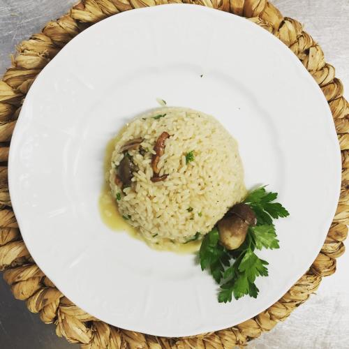 a white plate with a rice dish with meat and mushrooms at Albergo Villa Mario in Ischia