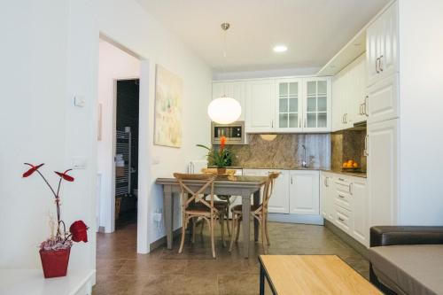 a kitchen with white cabinets and a table with chairs at La Casa dels Abeuradors in Gandesa