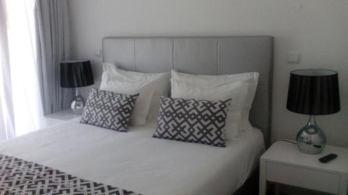 a bedroom with a white bed with pillows and two lamps at Pico Dreams in São Roque do Pico