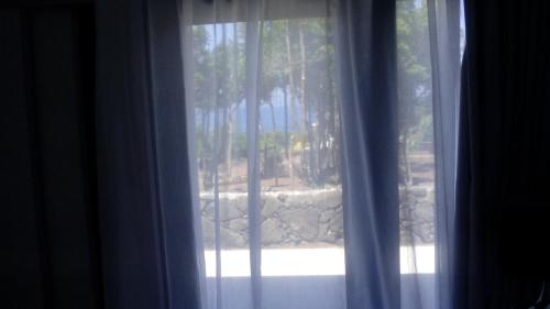 a window with a view of a stone wall at Pico Dreams in São Roque do Pico