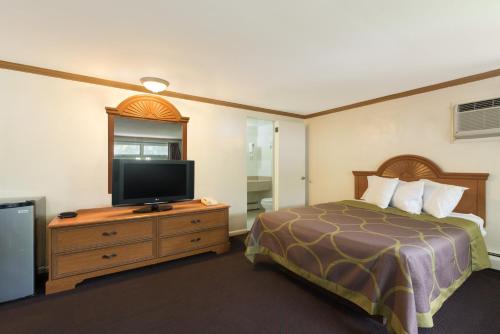a hotel room with a bed and a flat screen tv at Knights Inn Palmyra in Palmyra