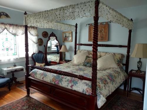 1 dormitorio con cama con dosel y espejo en Armistead Cottage Bed & Breakfast, en Newport