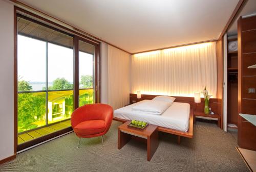a bedroom with a bed and a chair and a window at Marina Hotel am Starnberger See in Bernried