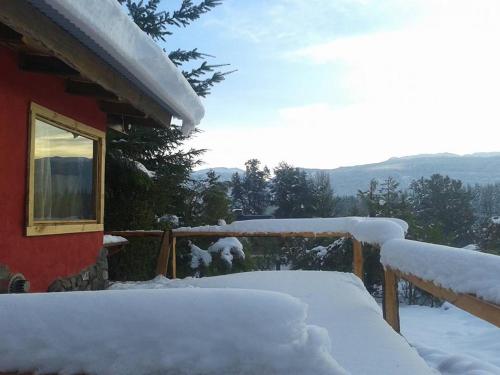 a house covered in snow next to a fence at Del Viejo Camino in El Bolsón