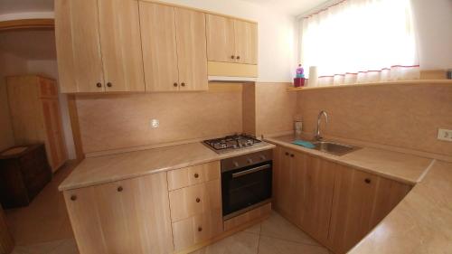 a kitchen with wooden cabinets and a stove and a sink at Apartmaji Katrč in Soča