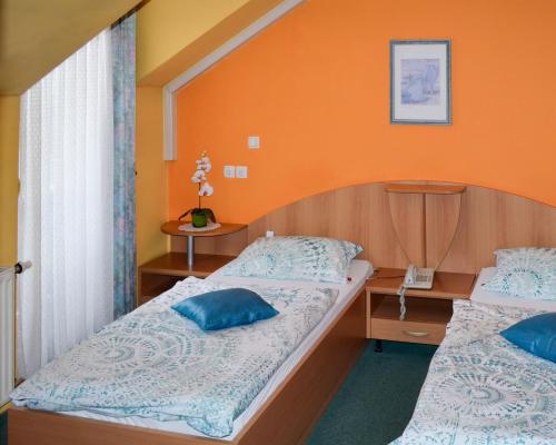 Dos camas en una habitación con una pared naranja. en Penzion Gostilna Keber, en Domžale