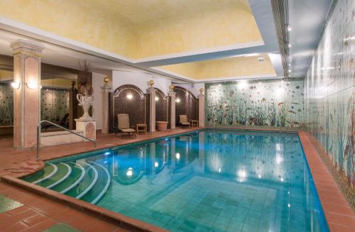 a large swimming pool in a hotel with a tile wall at Boutique Hotel Sunstar Brissago am Lago Maggiore in Brissago