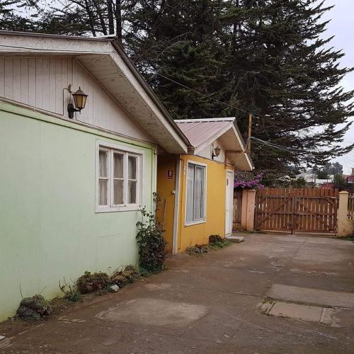 a green and yellow house with a gate and a driveway at Turismo el Bosque in Pichilemu