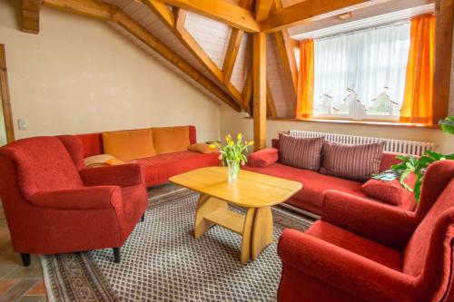 a living room with red couches and a table at Ferienwohnungen Ender in Sebnitz