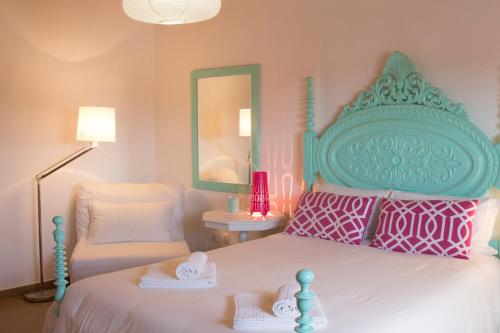 a pink and white bedroom with a bed and a chair at Alojamento Local Mira Mar in Zambujeira do Mar