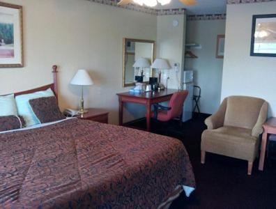 a hotel room with a bed and a chair and a desk at Western Inn Hamilton in Hamilton