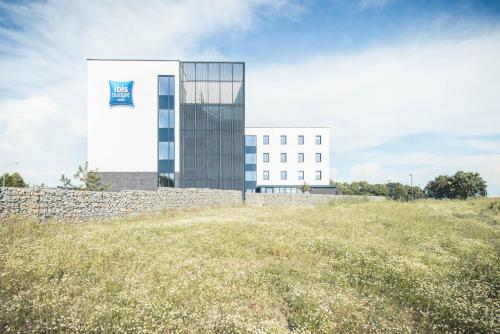 a building with a flag on the side of a field at ibis budget Troyes Est in Saint-Parres-aux-Tertres