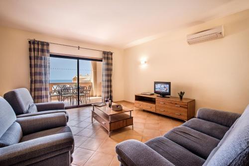 a living room filled with furniture and a tv at Estrela da Luz Resort in Luz