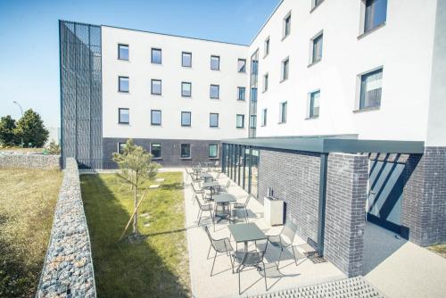 a building with chairs and tables outside of it at ibis budget Troyes Est in Saint-Parres-aux-Tertres