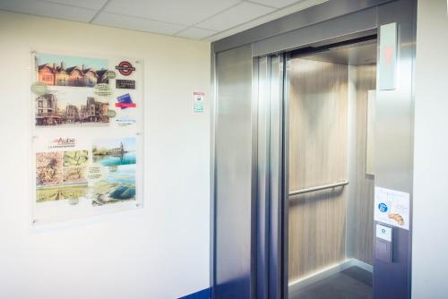 an elevator in a room with a poster on the wall at ibis budget Troyes Est in Saint-Parres-aux-Tertres