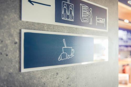 a sign on a wall with a cup of coffee at ibis budget Troyes Est in Saint-Parres-aux-Tertres