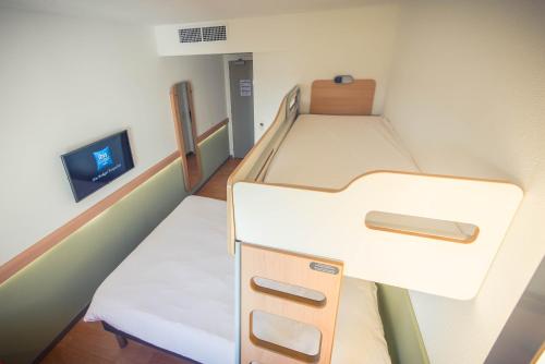 a small room with two beds and a tv at ibis budget Troyes Est in Saint-Parres-aux-Tertres