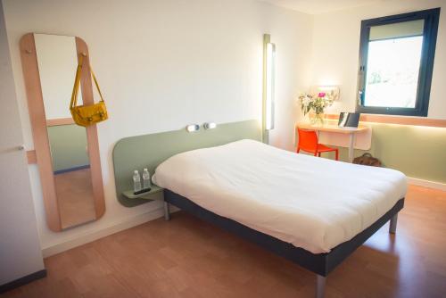 a bedroom with a large bed and a mirror at ibis budget Troyes Est in Saint-Parres-aux-Tertres