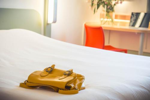 a brown purse sitting on top of a bed at ibis budget Troyes Est in Saint-Parres-aux-Tertres
