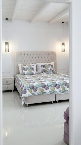 a white bedroom with a bed and two lights at Liberte Maisonettes in Parga