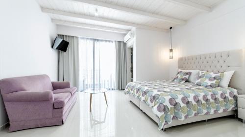 a bedroom with a bed and a chair at Liberte Maisonettes in Parga
