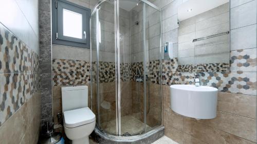 a bathroom with a shower and a toilet and a sink at Liberte Maisonettes in Parga