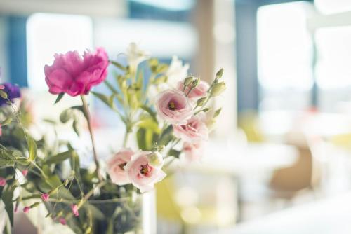 a vase filled with pink flowers in a room at ibis budget Troyes Est in Saint-Parres-aux-Tertres
