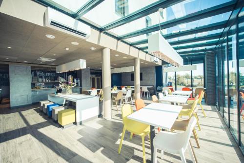 a dining area with tables and chairs in a building at ibis budget Troyes Est in Saint-Parres-aux-Tertres