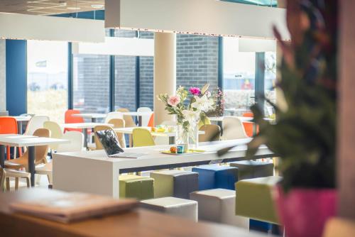 a cafeteria with a table with a laptop and flowers at ibis budget Troyes Est in Saint-Parres-aux-Tertres