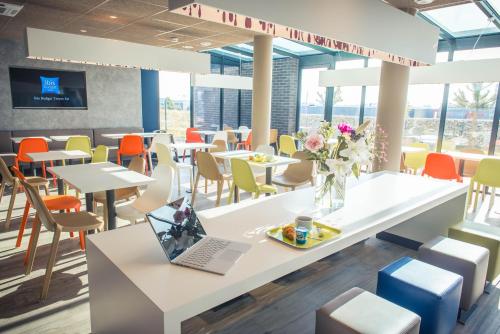a restaurant with tables and chairs and a laptop on a table at ibis budget Troyes Est in Saint-Parres-aux-Tertres