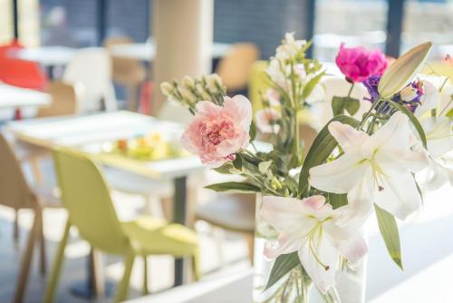 a vase filled with flowers sitting on a table at ibis budget Troyes Est in Saint-Parres-aux-Tertres
