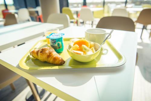 a tray with a plate of food and a bowl of fruit at ibis budget Troyes Est in Saint-Parres-aux-Tertres