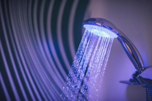 a blue shower head in a room with a curtain at ibis budget Troyes Est in Saint-Parres-aux-Tertres